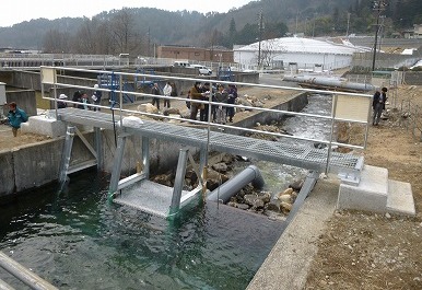伊賀良井取り入れ口に設置されたマイクロ水力発電設備と関係者